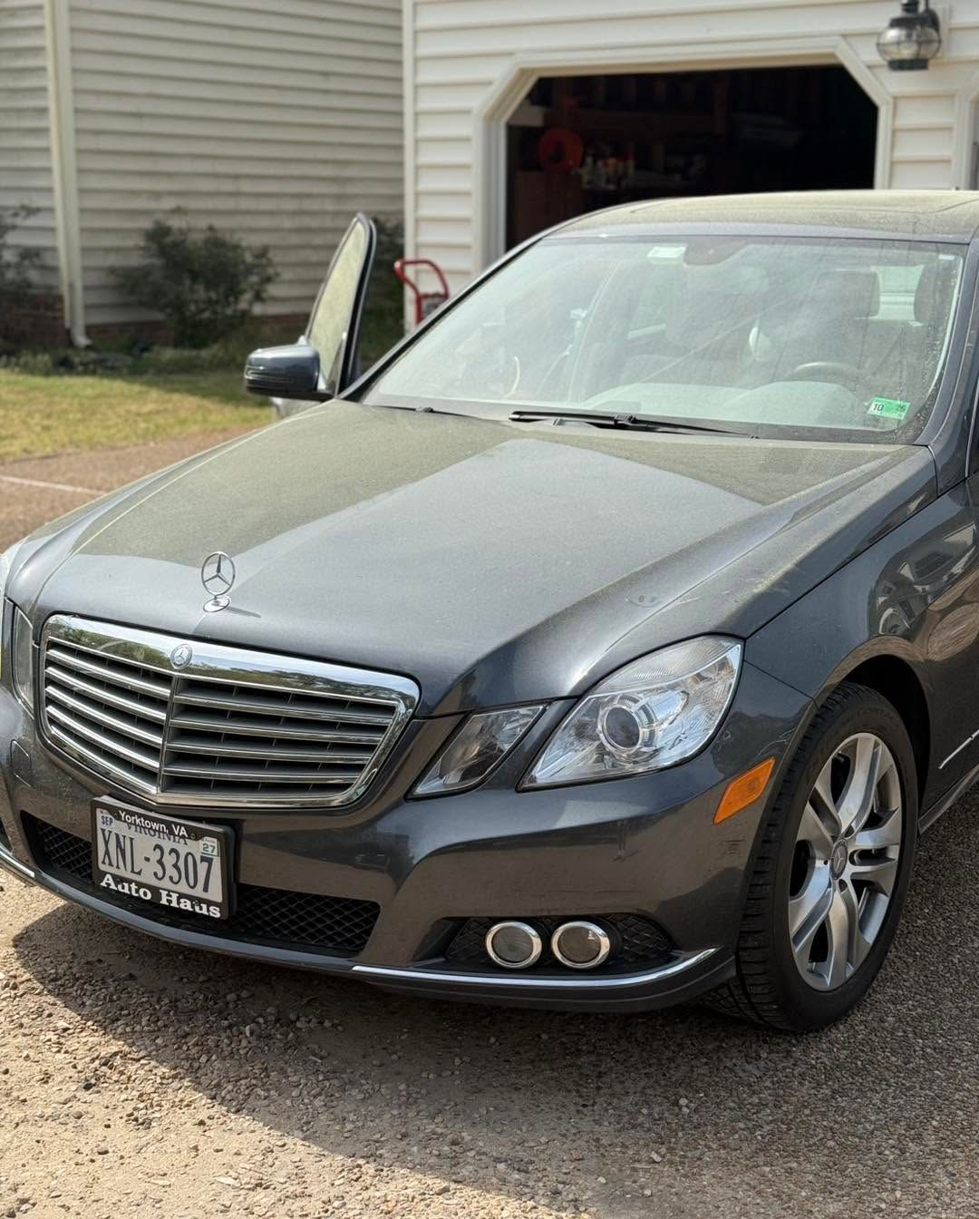 Gray Mercedes sedan parked in a driveway in front of an open garage