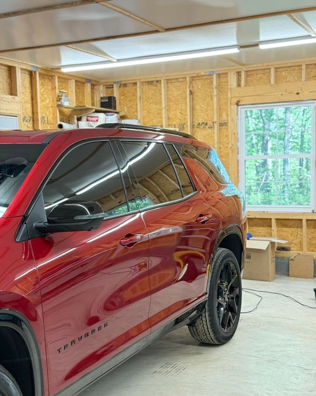 Red SUV in a garage/workshop, with a glossy finish and a large window in the background.
