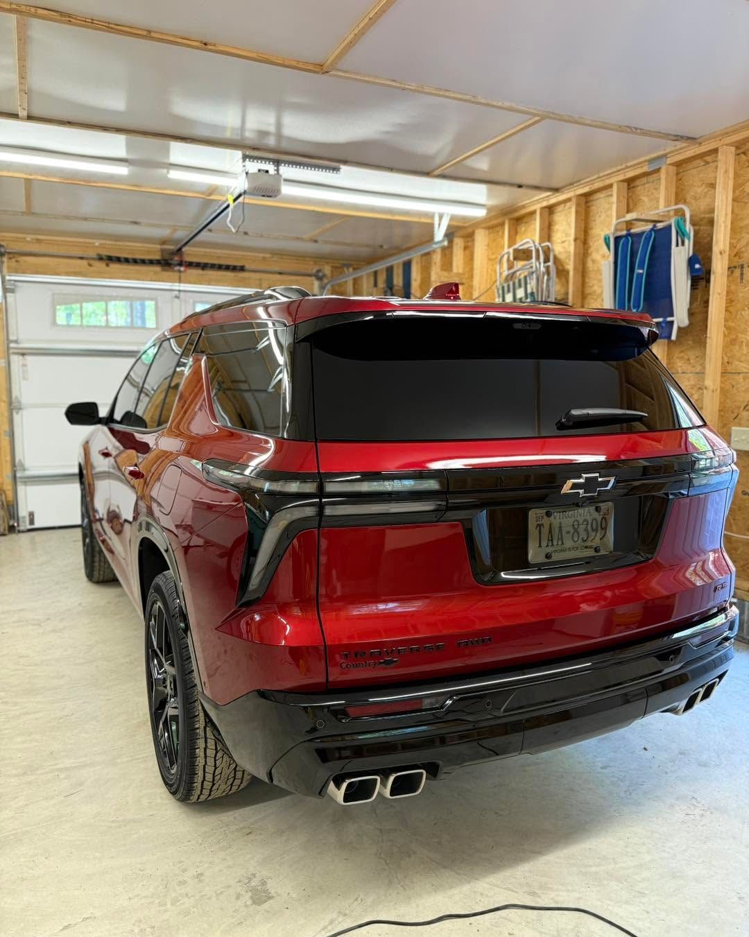 Red SUV parked inside a wooden garage, rear view, with tinted windows and dual exhausts.