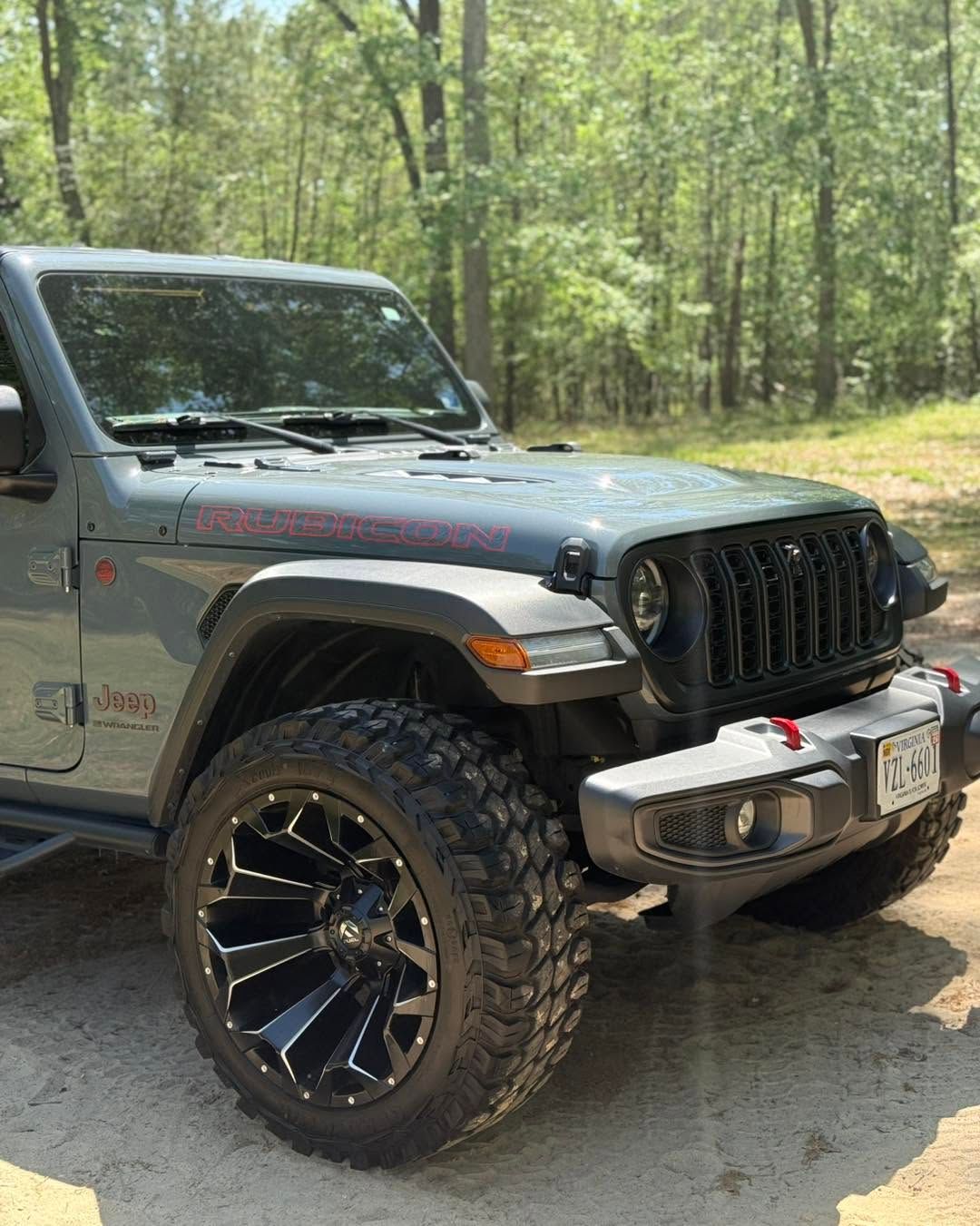 Gray off-road Jeep with oversized tires parked on a forest trail