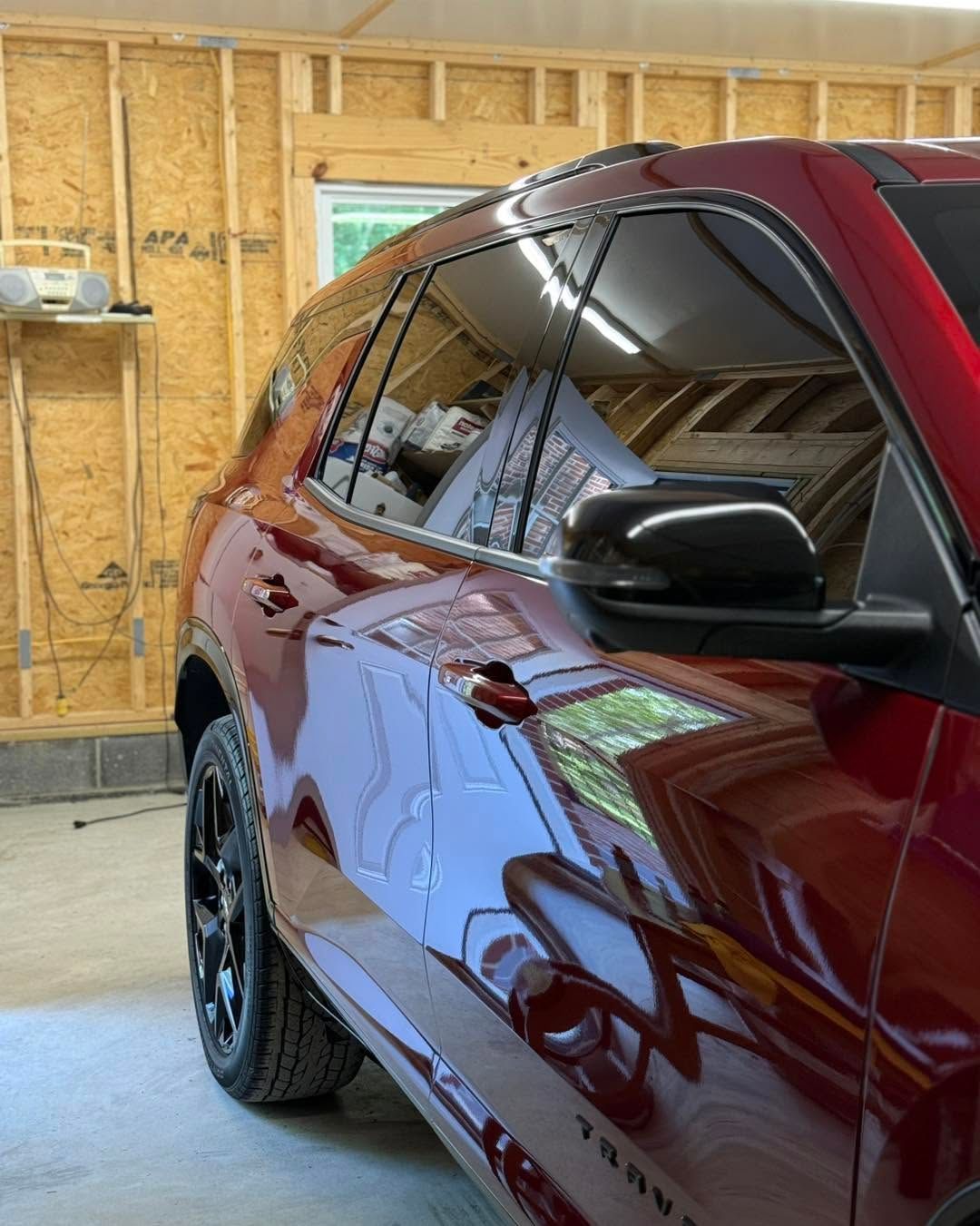 Maroon SUV parked in a garage, showing its side and tinted windows.