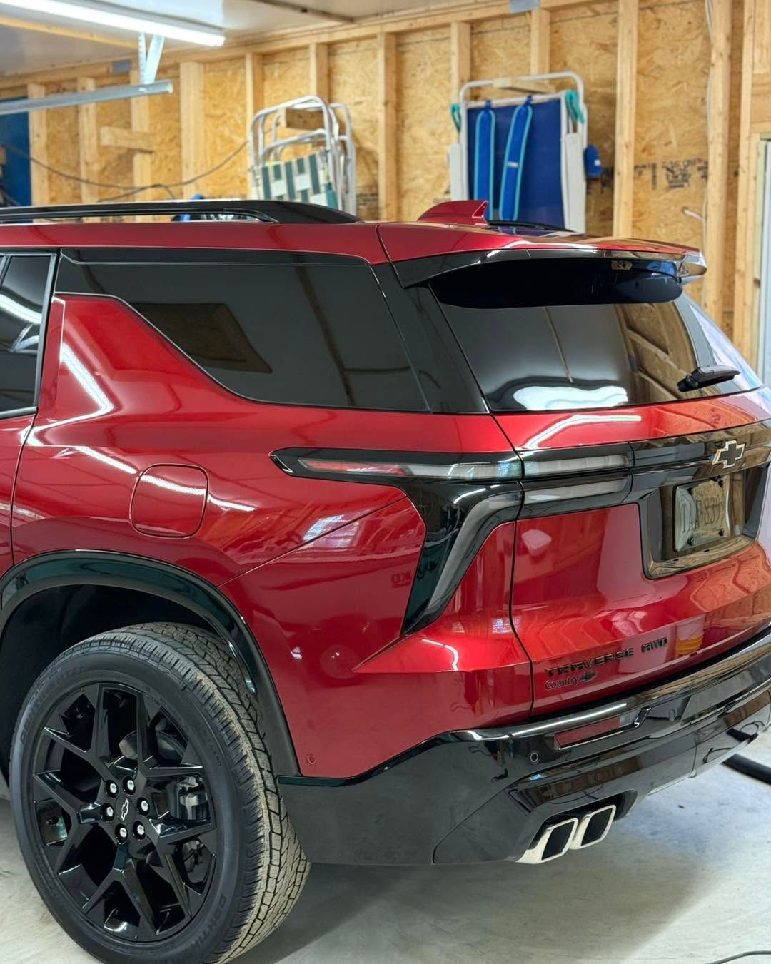 Red SUV parked in a garage, rear view with black trim and tinted windows.