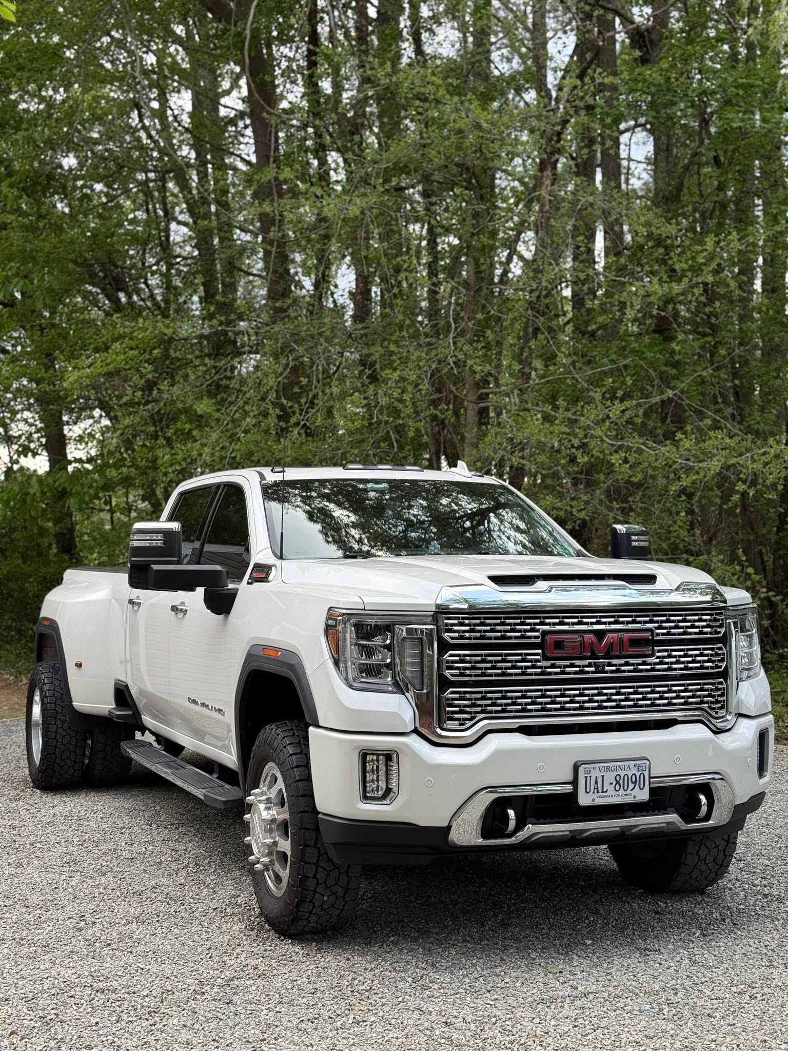White GMC pickup truck parked on a dirt road in a wooded area