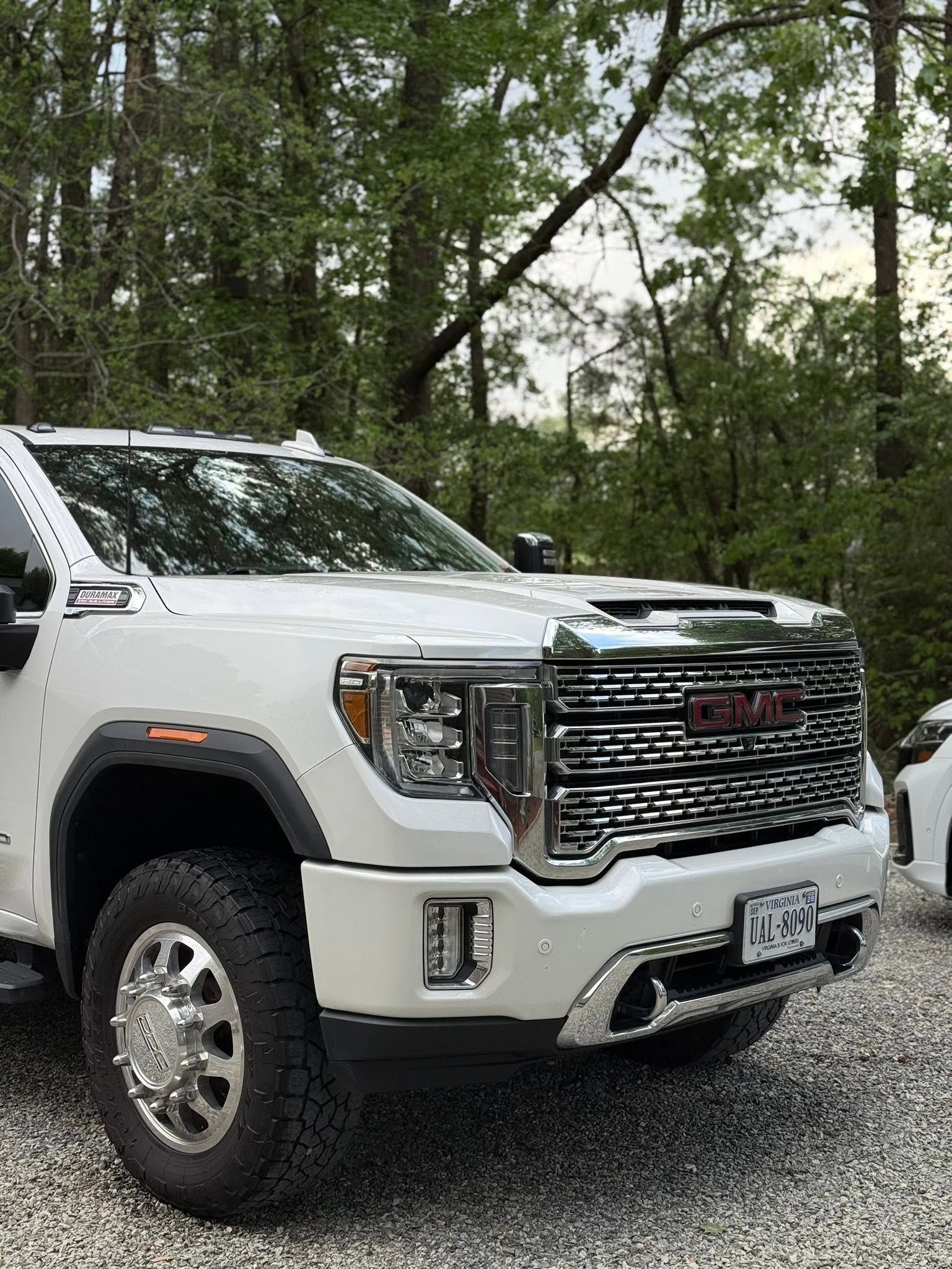 White GMC pickup truck parked on gravel with trees in the background