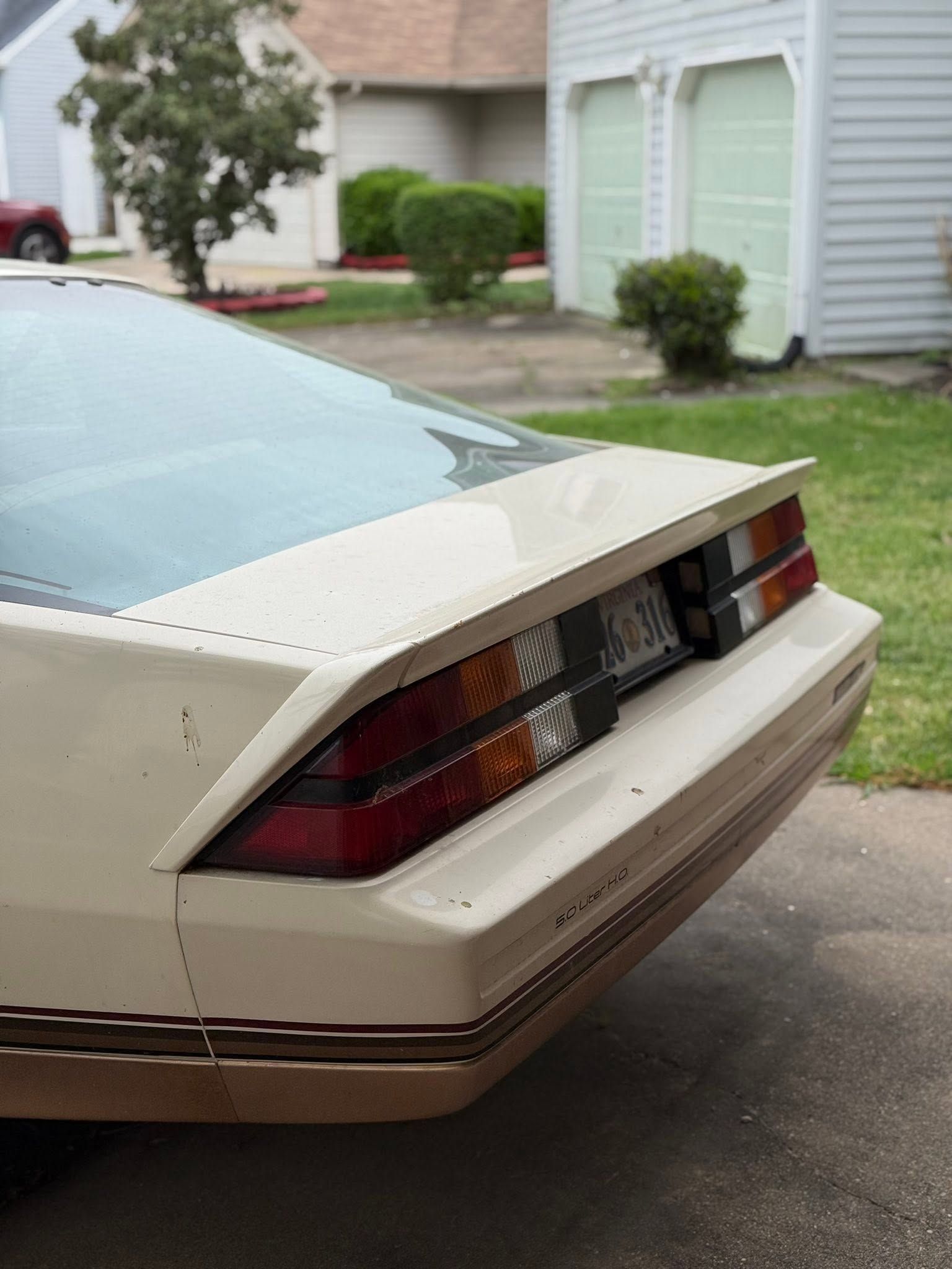 Rear corner of a beige sports car parked on a residential street.
