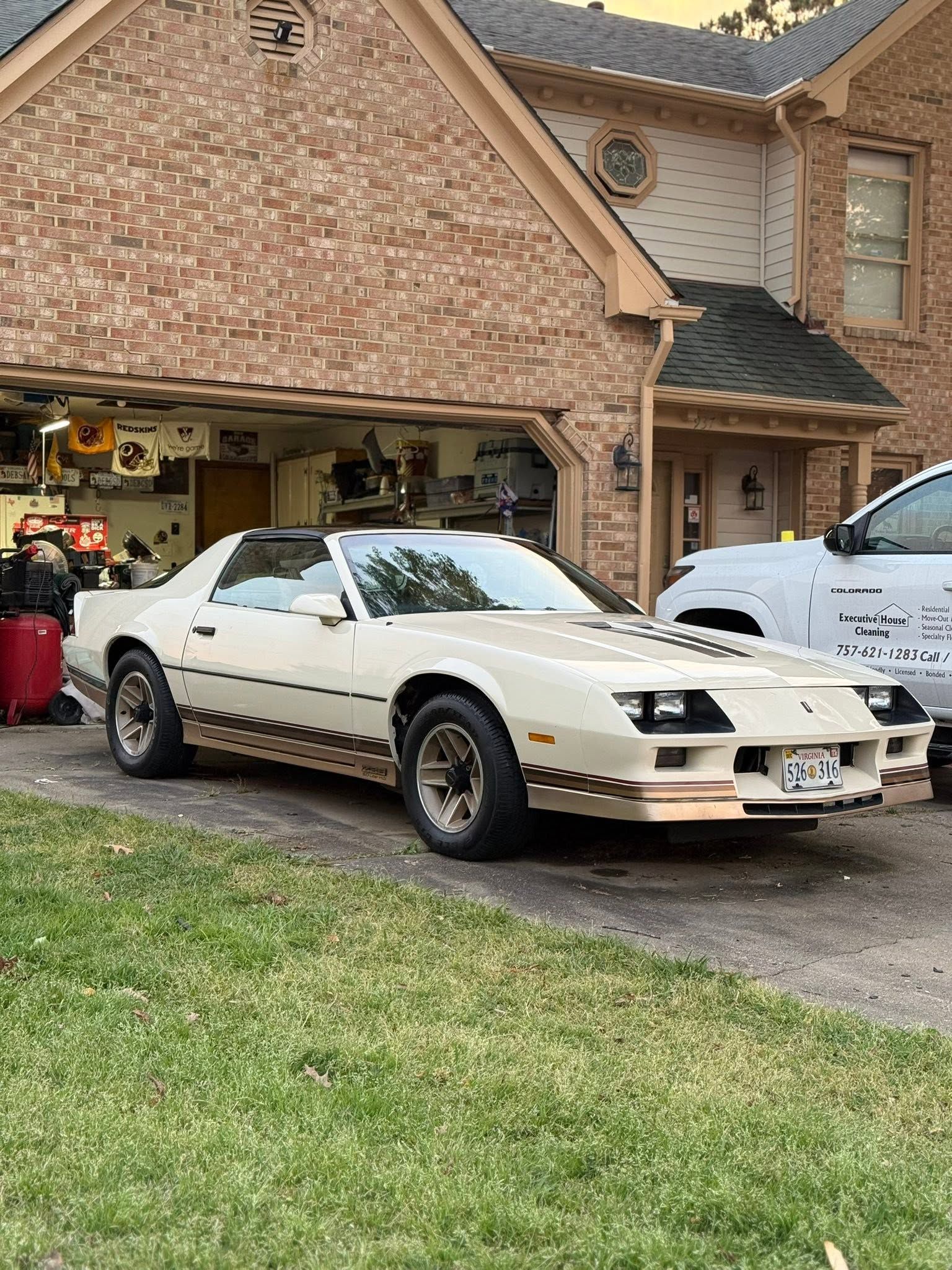 White sports car parked in a driveway in front of a brick house