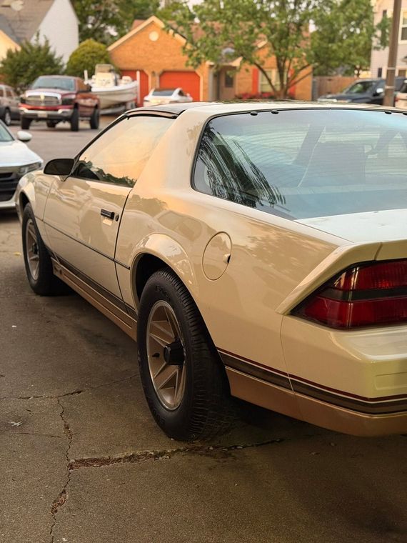 White sports car parked on a wet street in a suburban neighborhood at dusk