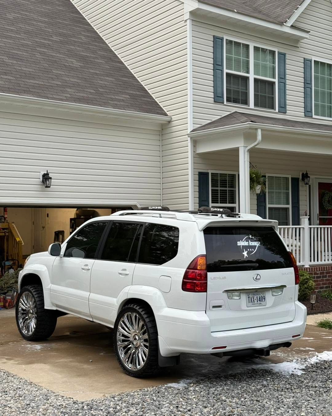 White SUV parked in a driveway beside a beige townhouse garage and porch