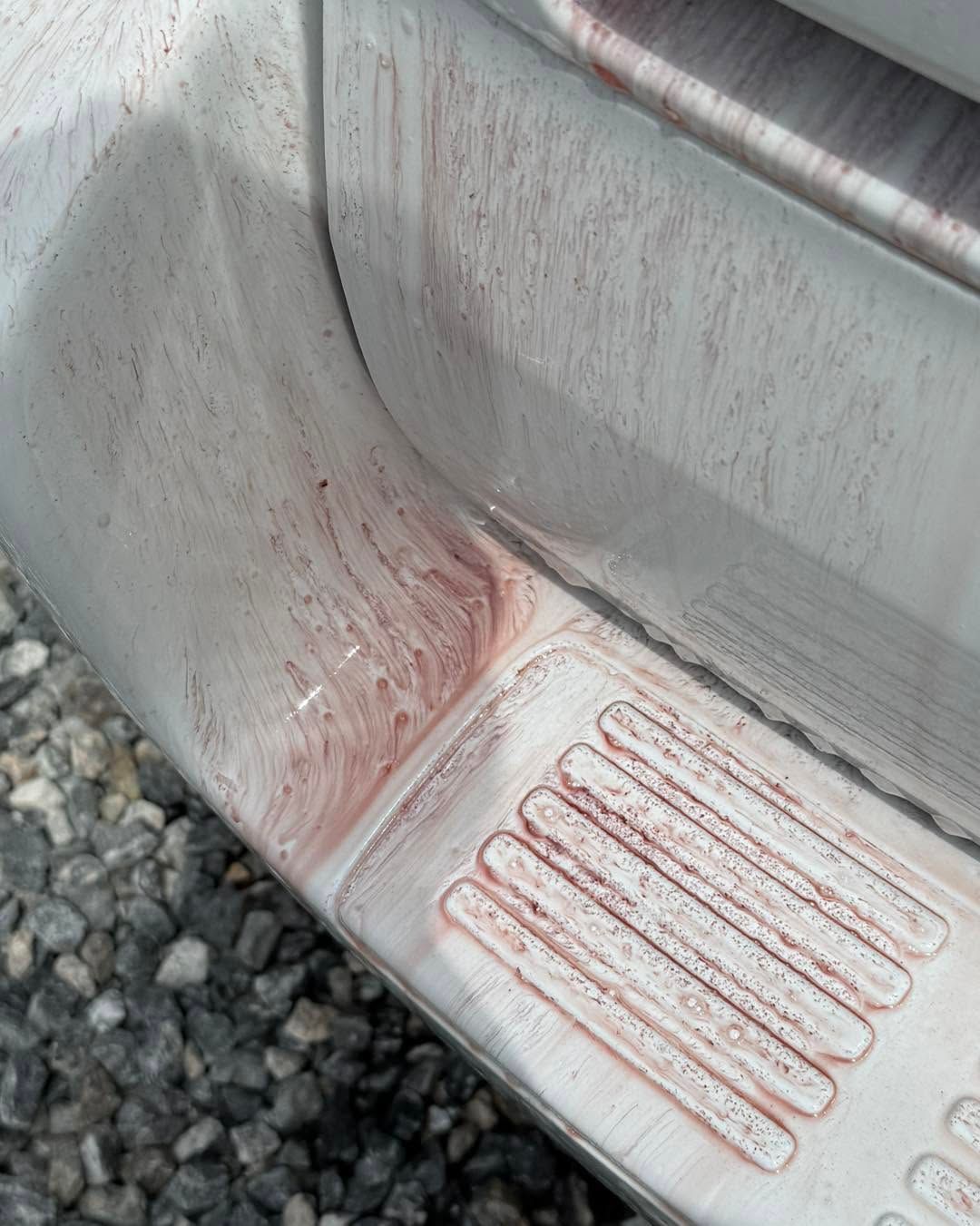 Close-up of a silver car panel with red scuff marks and scratched step plate near the wheel well