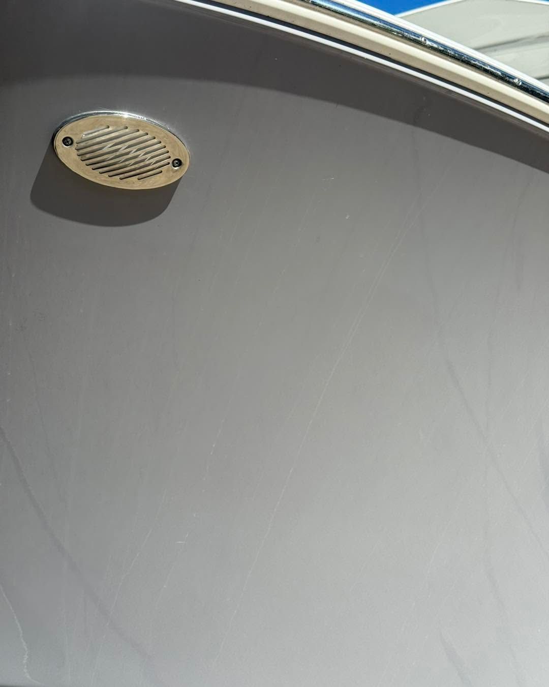 Oval vent on a gray wall near a window or ceiling edge