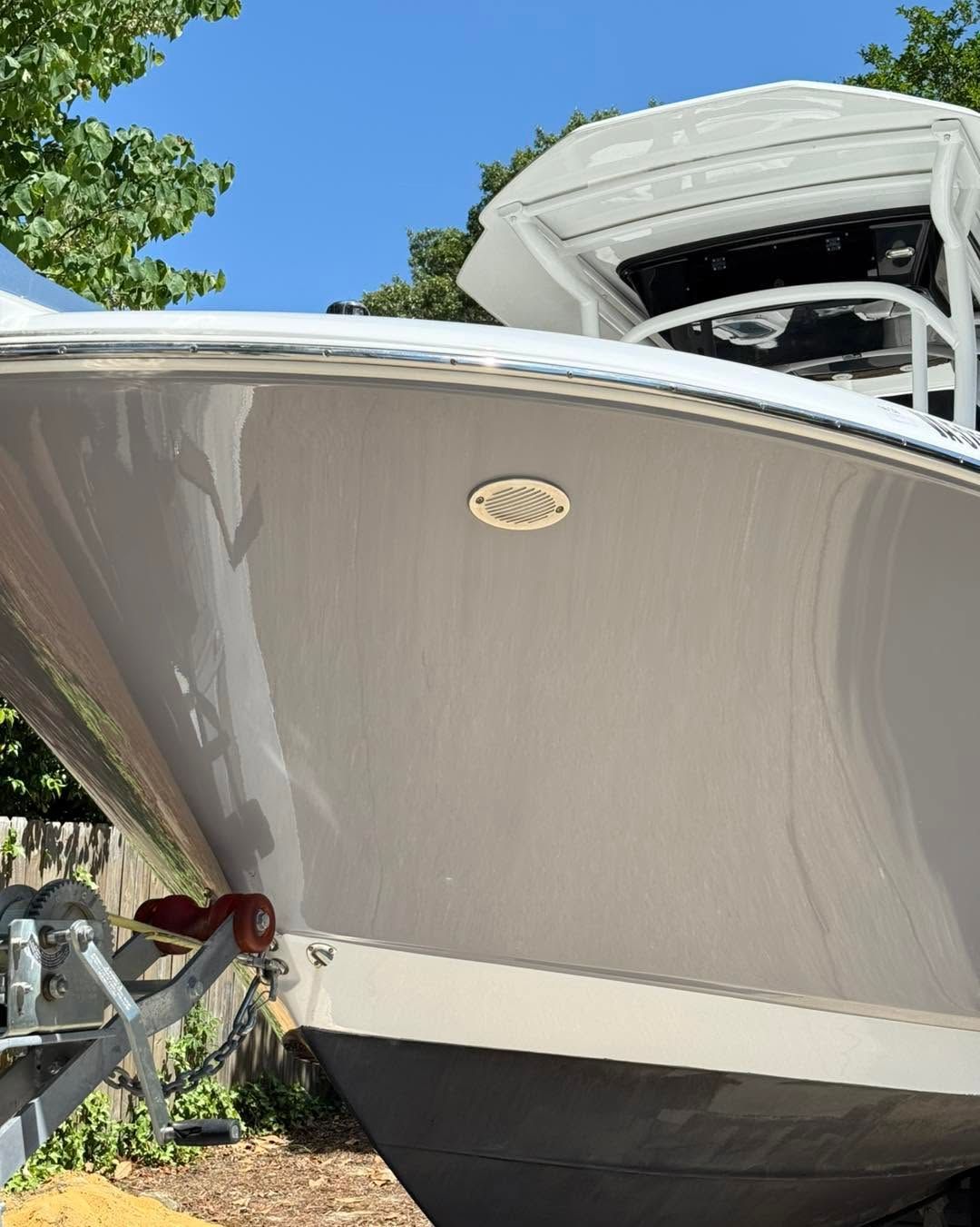 Bow of a large white and gray boat docked outdoors under a blue sky.