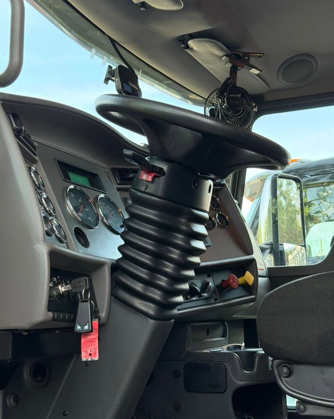 Truck cab interior with a black suspension seat and dashboard controls visible.