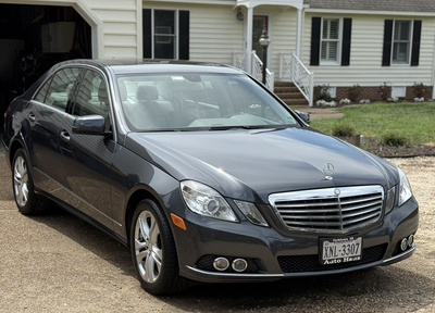 Dark gray sedan parked in a driveway in front of a suburban house