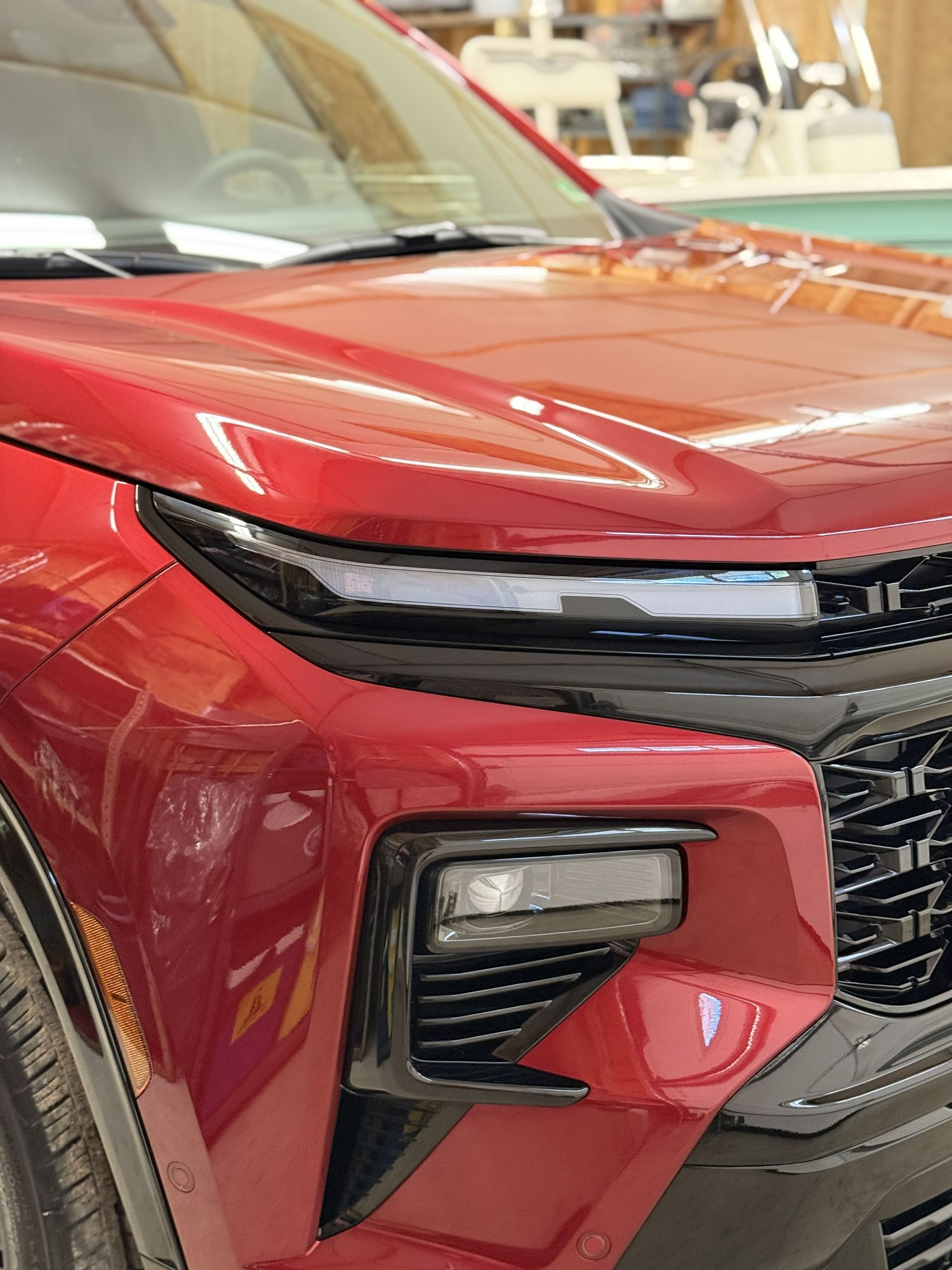 Front view of a red SUV’s headlight and grille in an indoor showroom