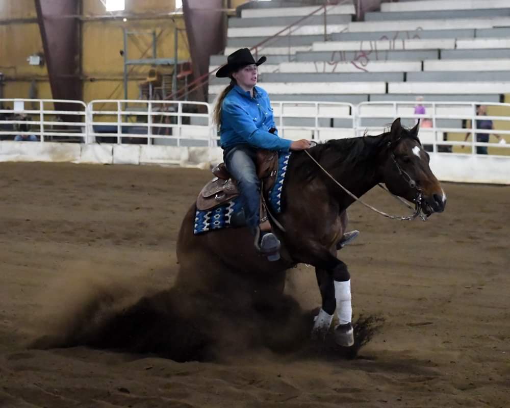 A woman in a cowboy hat is riding a brown horse