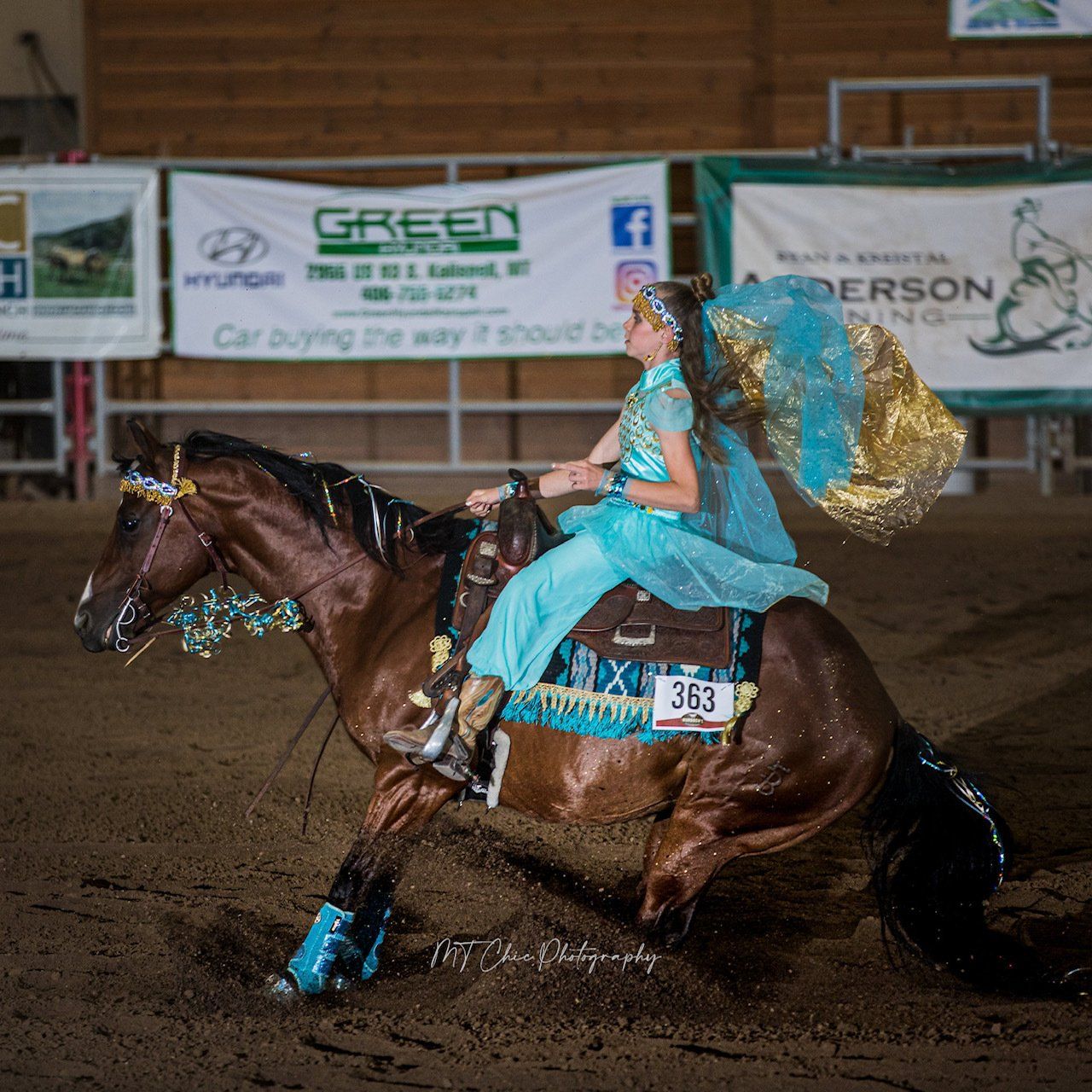 A woman in a blue dress is riding a brown horse.