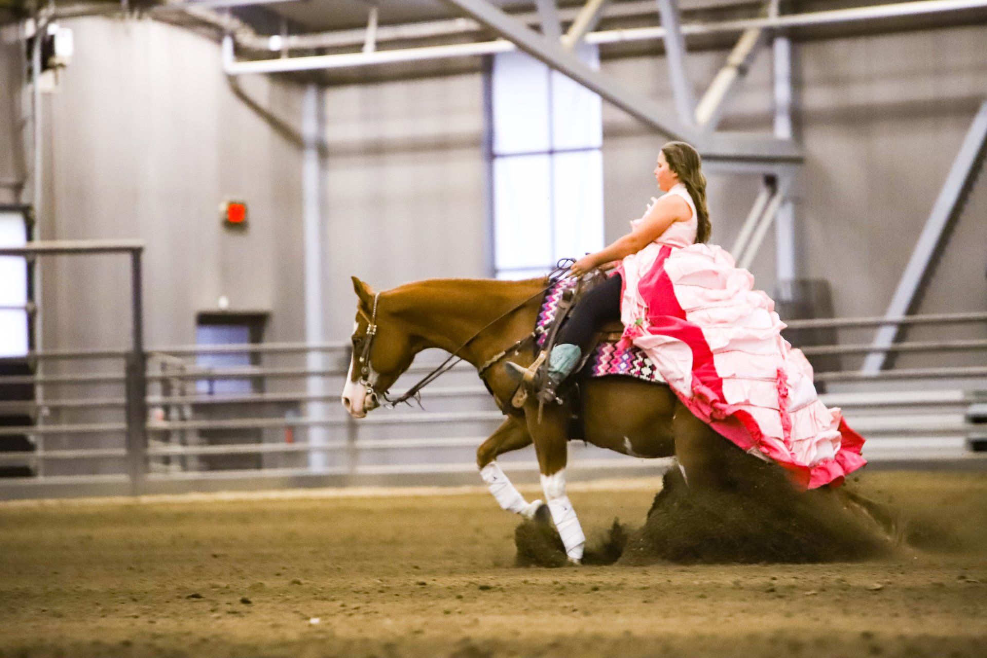 A woman in a pink dress is riding a brown horse