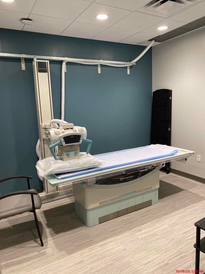 X-ray room with examination table, imaging equipment, and blue accent wall.