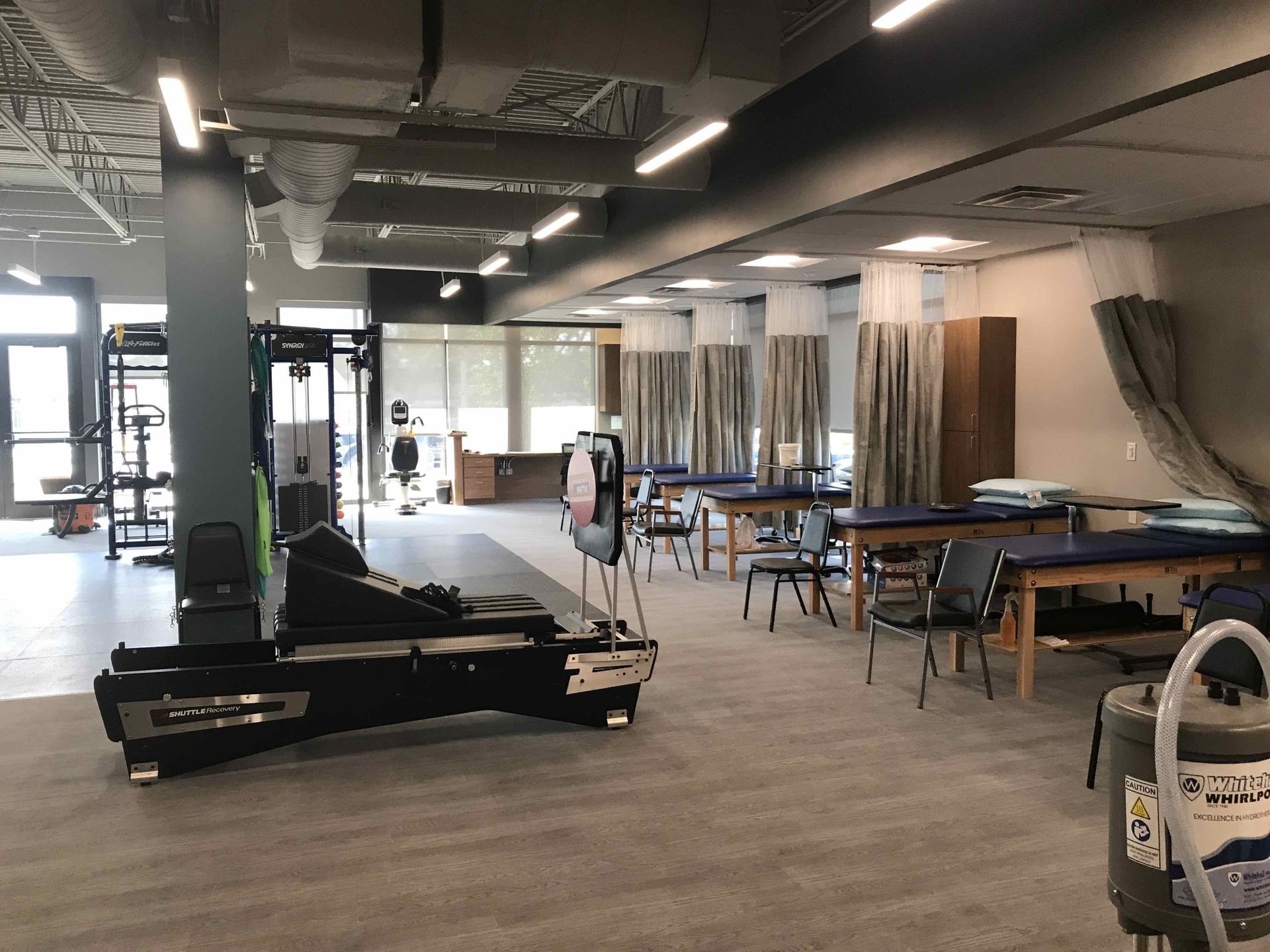 Physical therapy gym with exercise equipment and treatment tables.