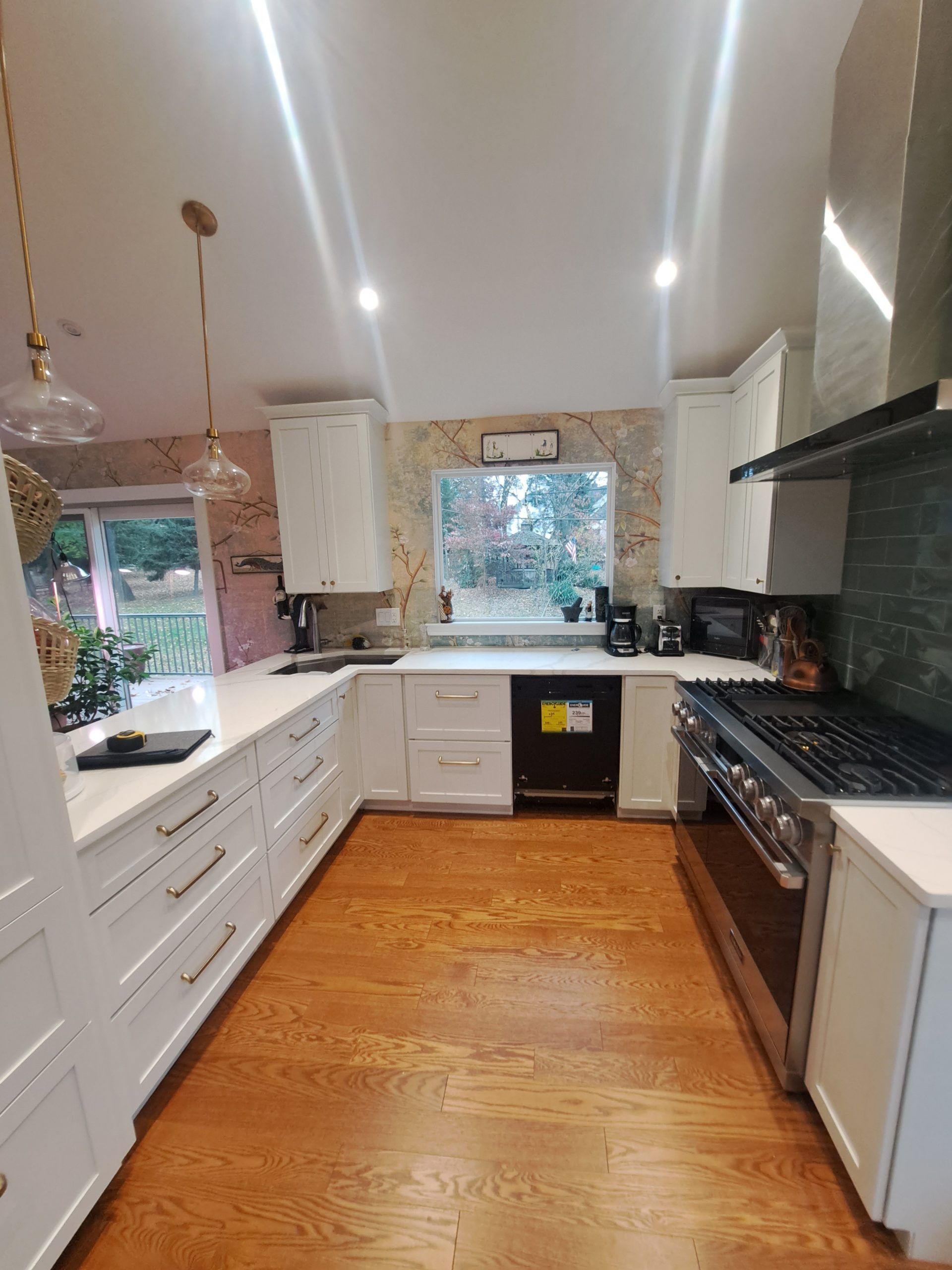 Gray kitchen with upper and lower cabinets, white countertop, marble backsplash, and gold faucet.