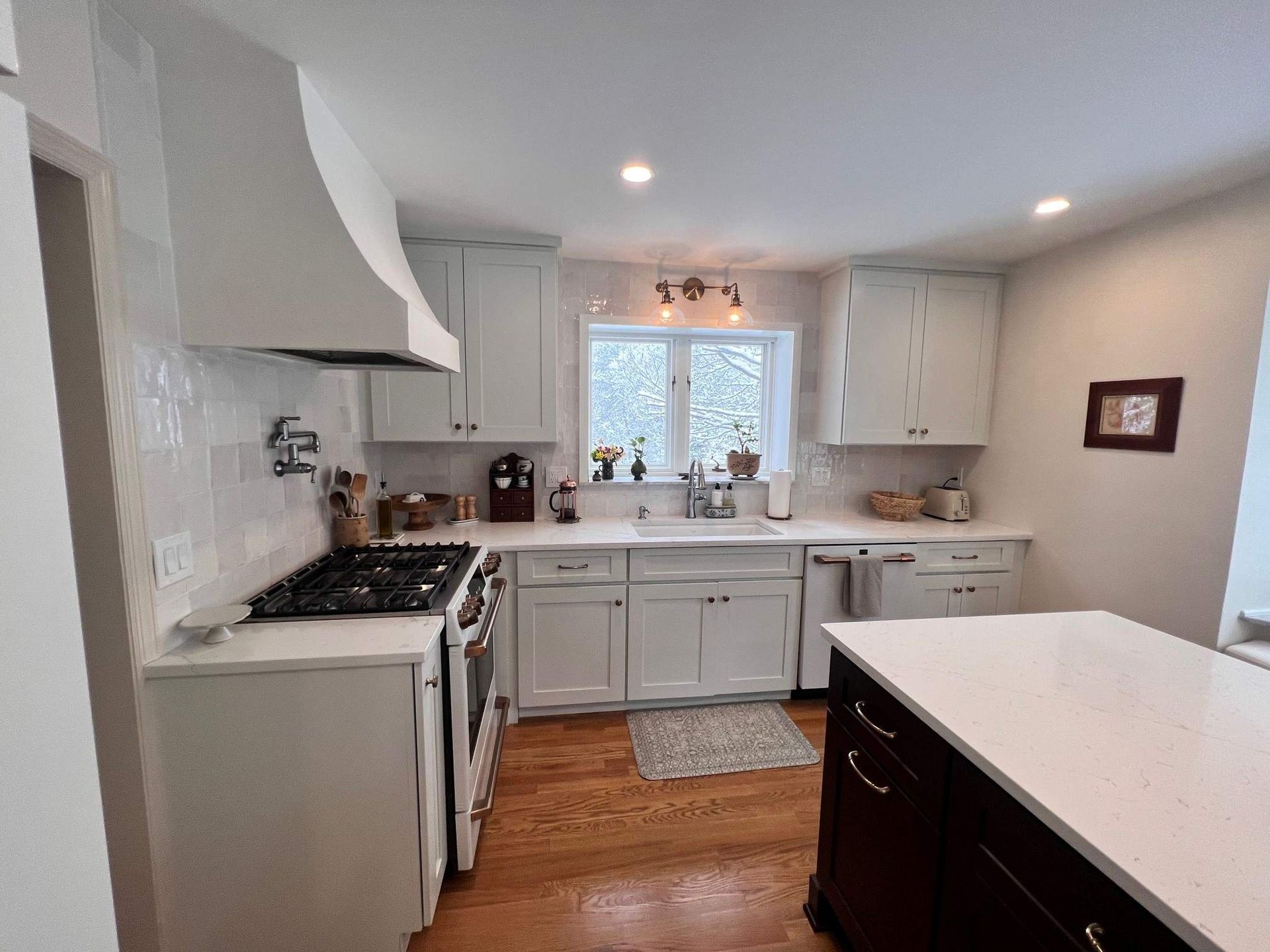 Kitchen with white cabinets, stainless steel appliances, and wood floors.