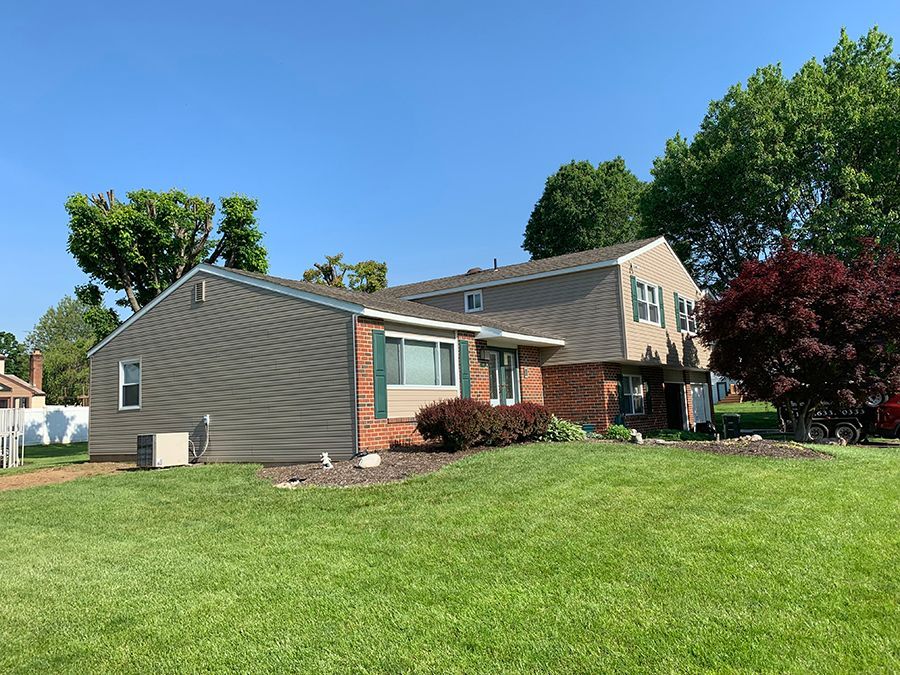 Tan and brown townhome with green grass and a bright blue sky.