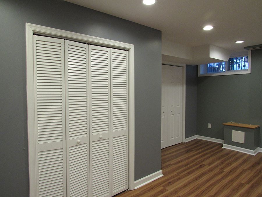 Interior of a room with gray walls, white trim, wood-look flooring, and a white louvered closet.