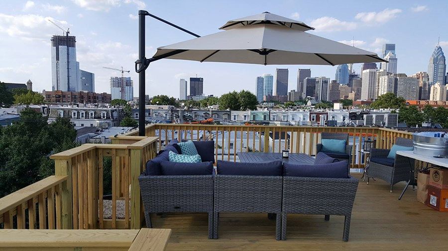 Rooftop deck with modern furniture, a large umbrella, and city skyline view.