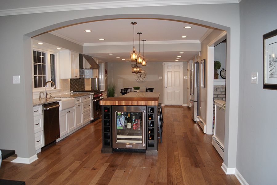 Open-concept kitchen with hardwood floors, a central island with a wine fridge, and a view into a dining area.