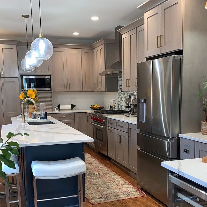 Modern kitchen with gray cabinets, white countertops, and a blue island with white stools.