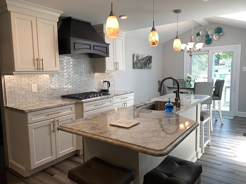 Bright, renovated kitchen with white cabinets, gray countertops, an island, and pendant lights.