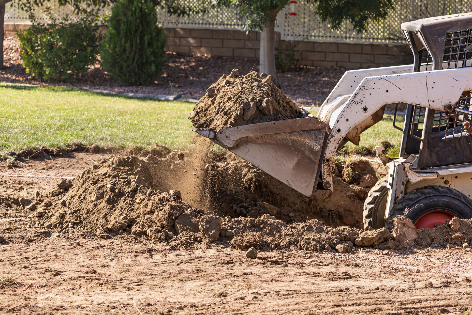 Bobcat chargeant de la terre sur un tas sur un chantier de construction.
