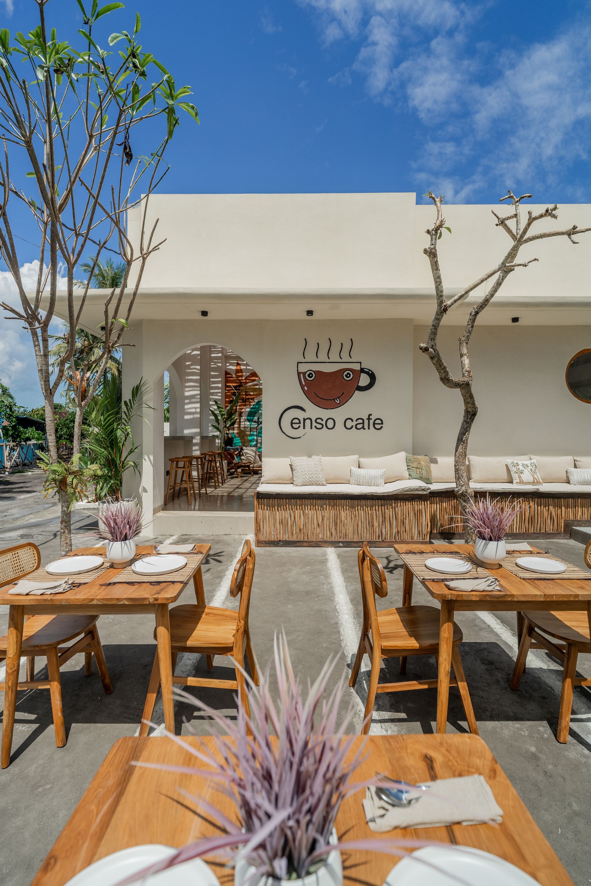 Modern villa patio with pool, wicker lounge chairs, and tropical tree beside large glass doors