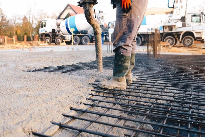 Construction worker pouring concrete over rebar at a worksite