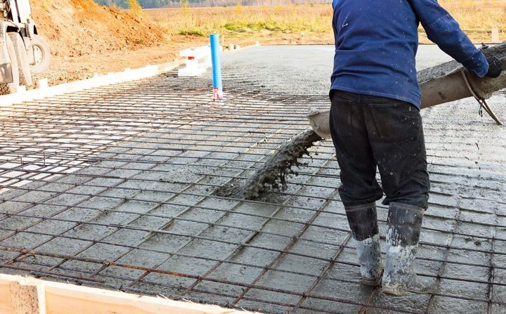 Worker smoothing wet concrete with a trowel on a construction site