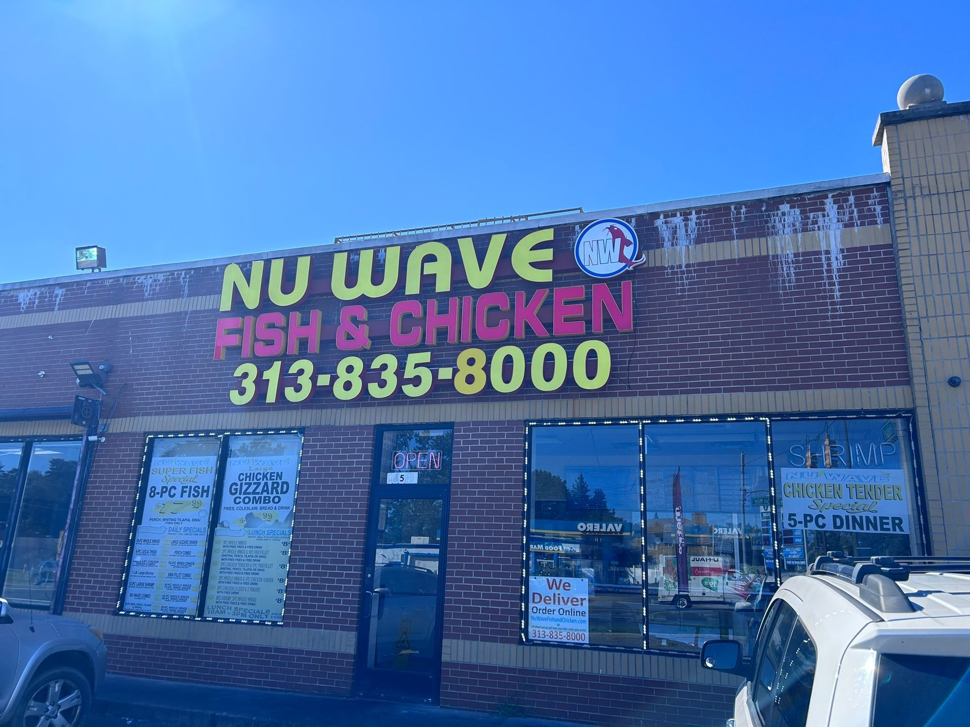 Nu Wave Fish & Chicken storefront with neon sign and phone number on a sunny street