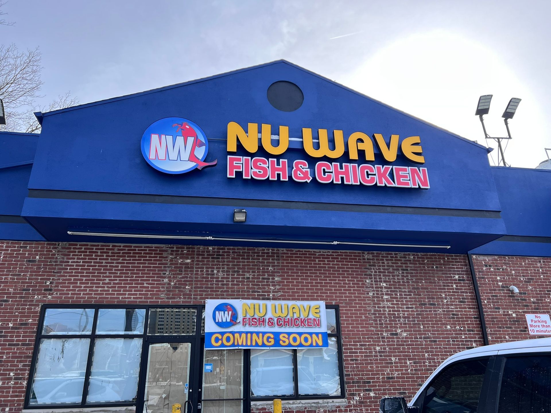 NU WAVE Fish & Chicken storefront with blue sign on a brick building, plus a “Coming Soon” banner below