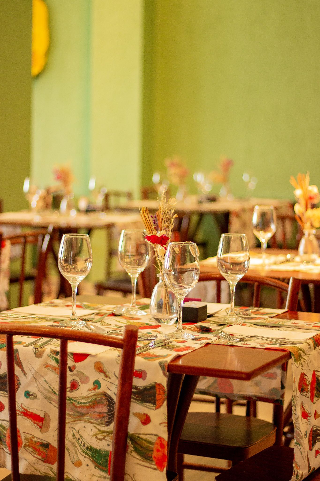 Um restaurante cheio de mesas e cadeiras com taças de vinho sobre elas.