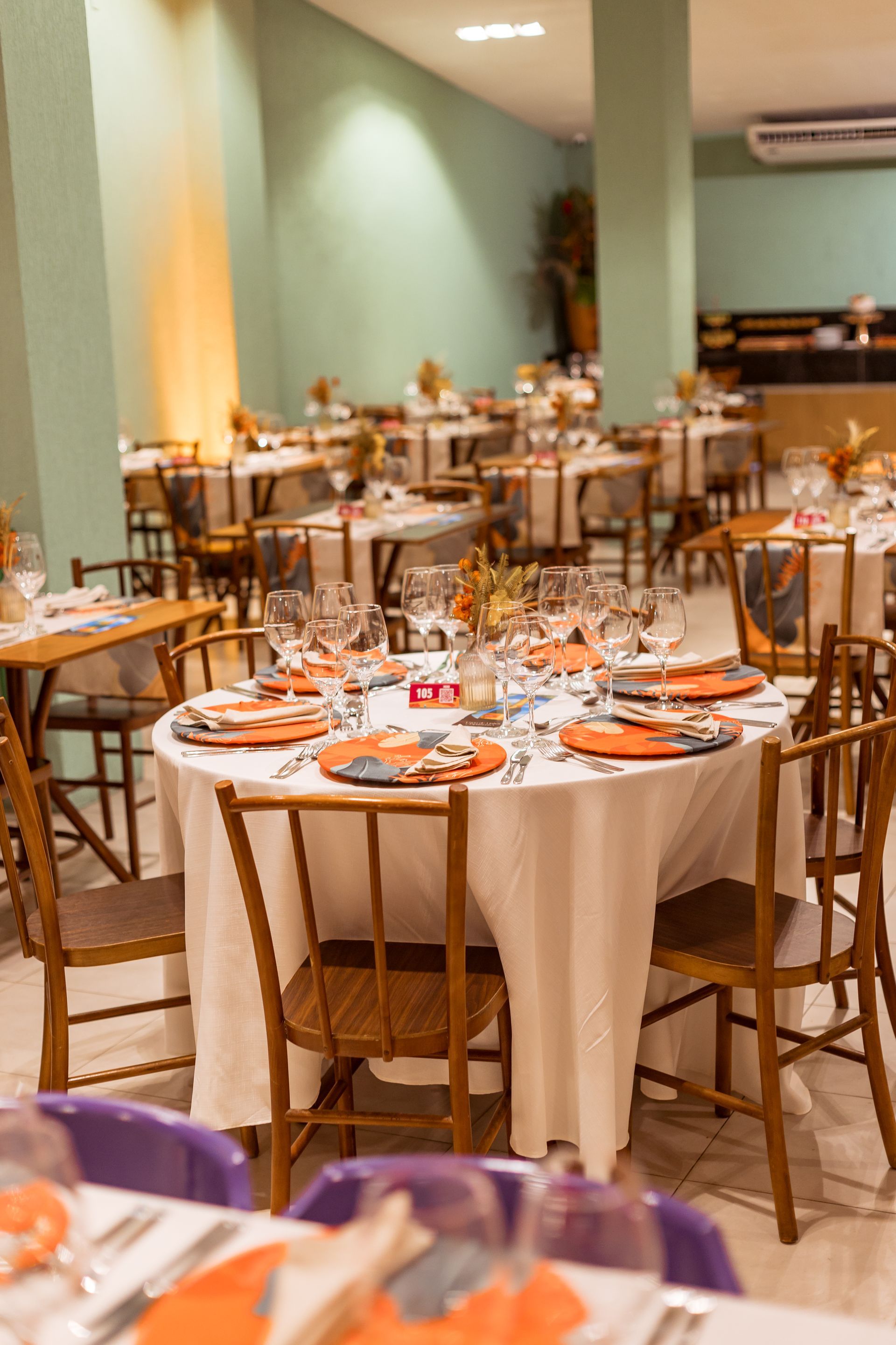Uma sala de jantar cheia de mesas e cadeiras preparada para uma festa.