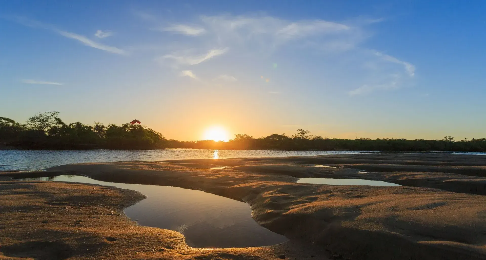 O sol está se pondo sobre um corpo d'água.