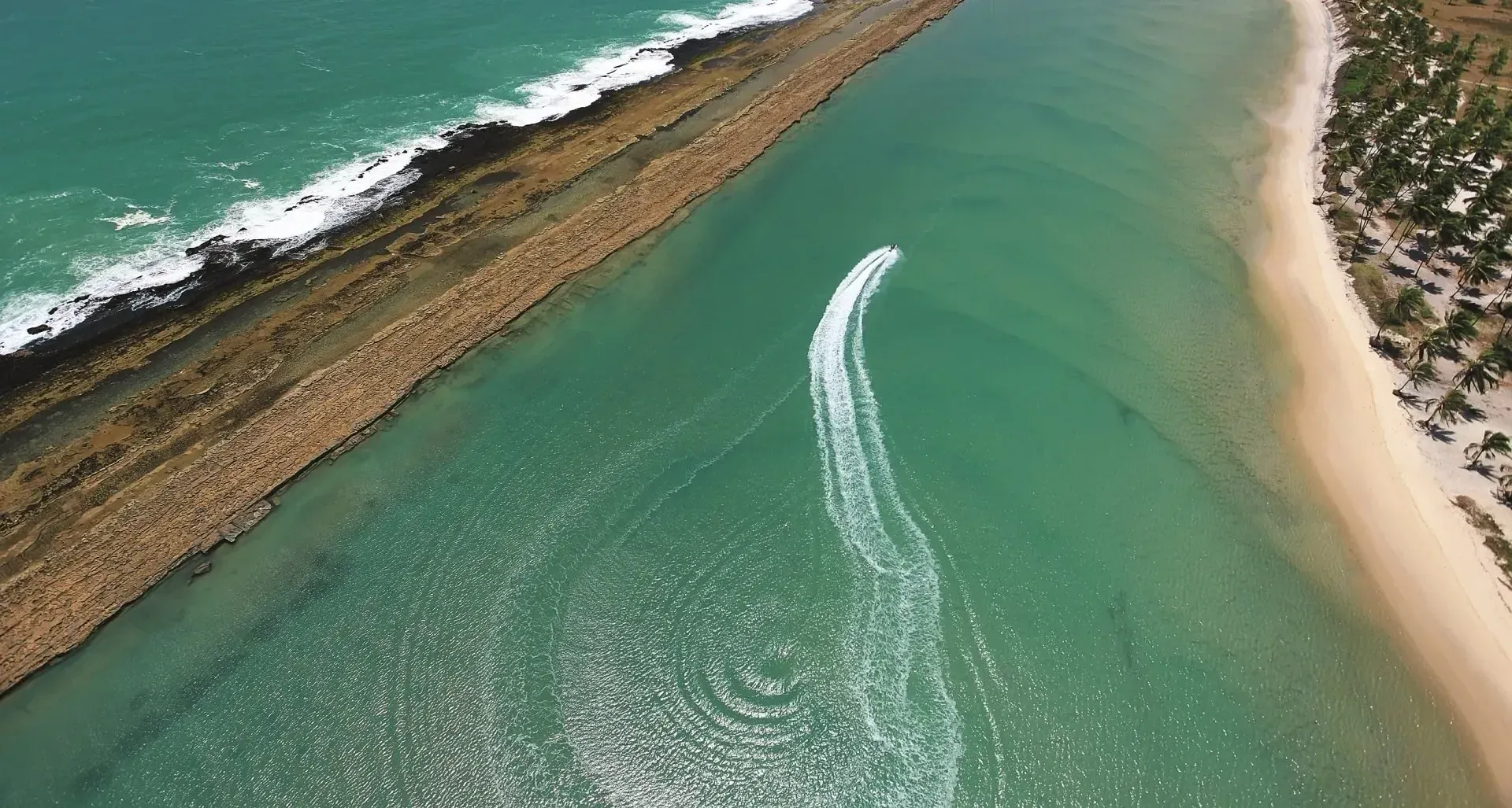 Uma vista aérea de um barco no oceano perto de uma praia.