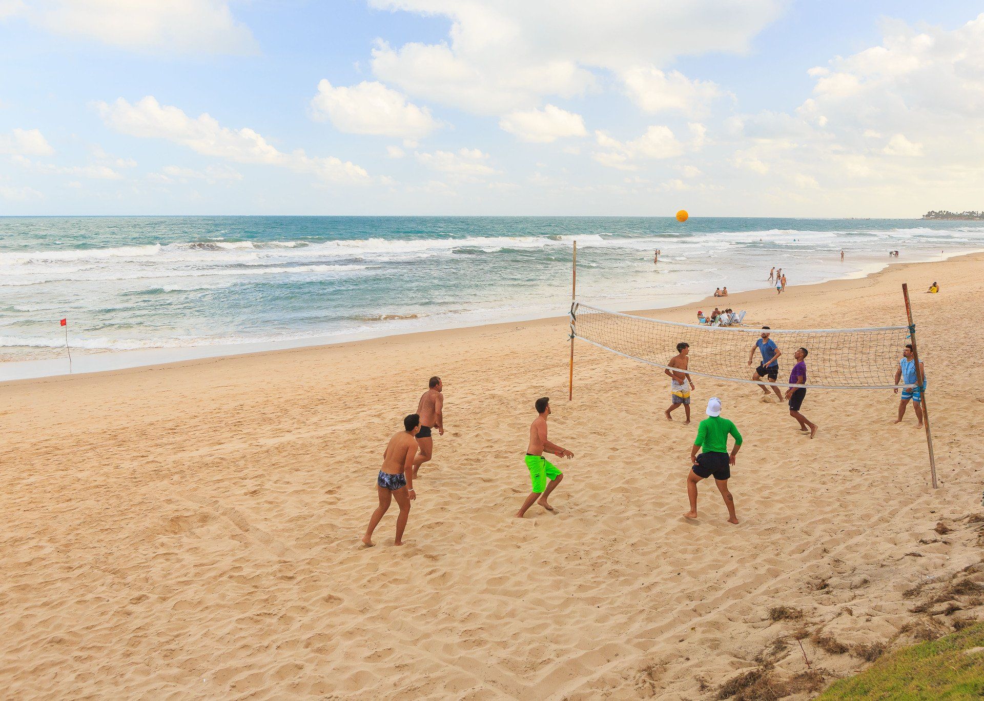 Um grupo de pessoas está jogando vôlei na praia.