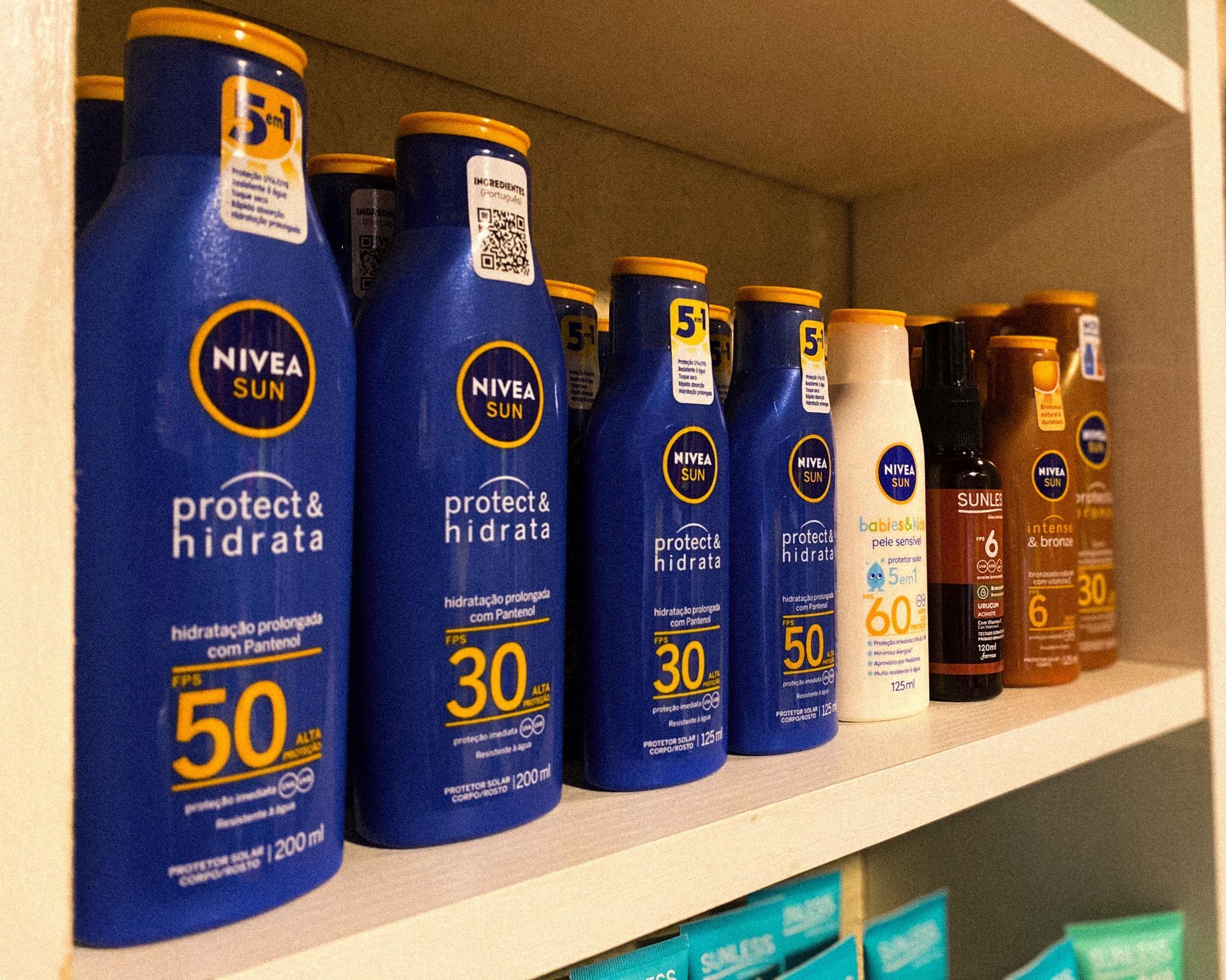 Vários frascos de protetor solar nivea estão alinhados em uma prateleira