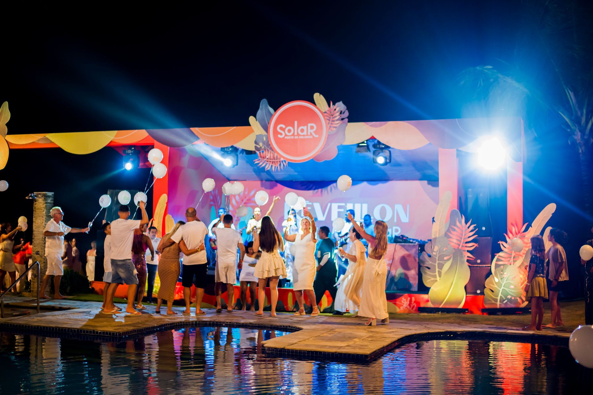 Um grupo de pessoas está dançando em frente ao palco em uma festa.