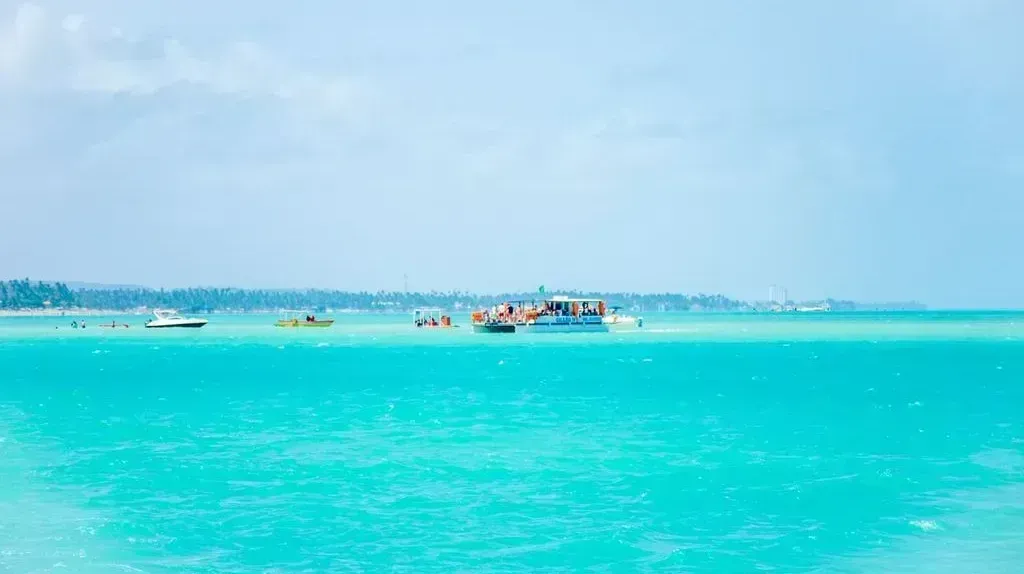 Um grupo de barcos flutua sobre um oceano azul-turquesa.