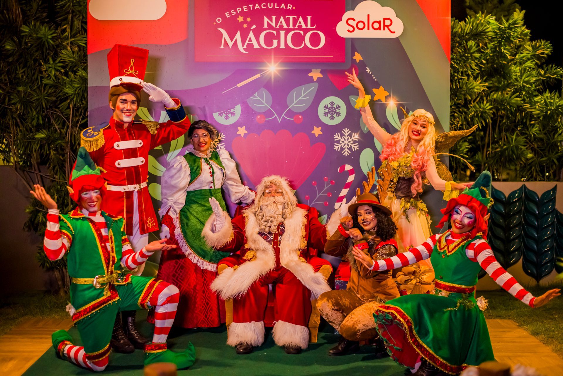 Um grupo de pessoas vestidas de papai noel e elfos estão posando para uma foto.
