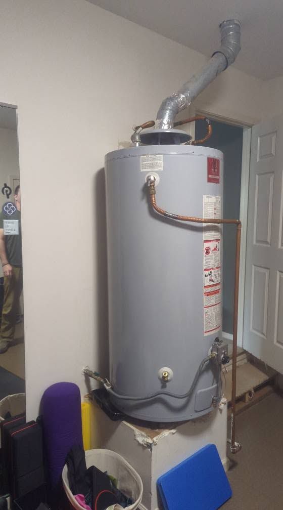 Gray water heater with vent pipe in a utility closet beside a doorway