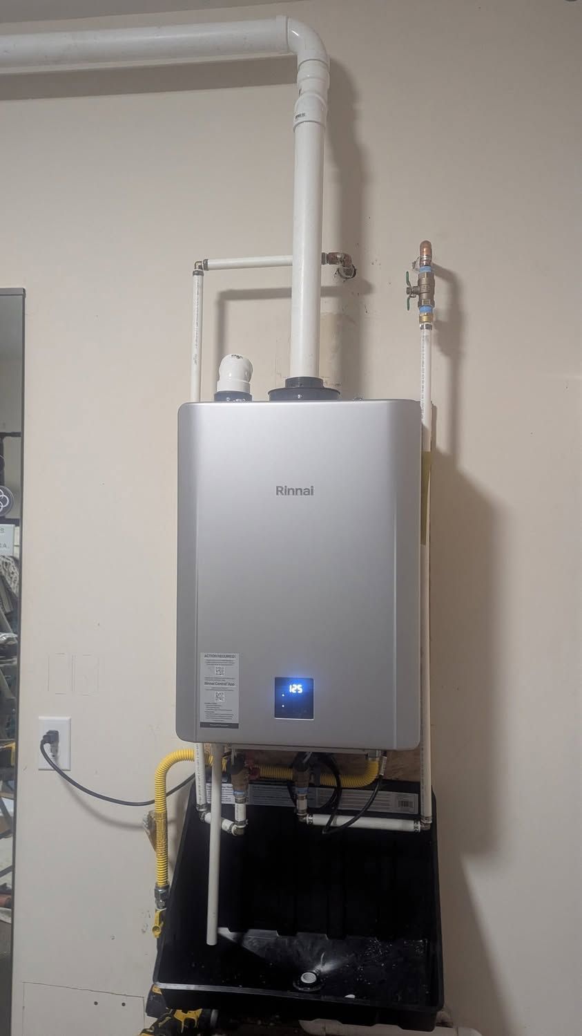 Wall-mounted white water heater with pipes and a blue digital display in a utility room