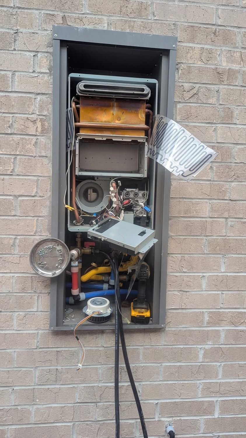 Open electrical panel mounted in a brick wall, with exposed wiring, dials, and metal components.