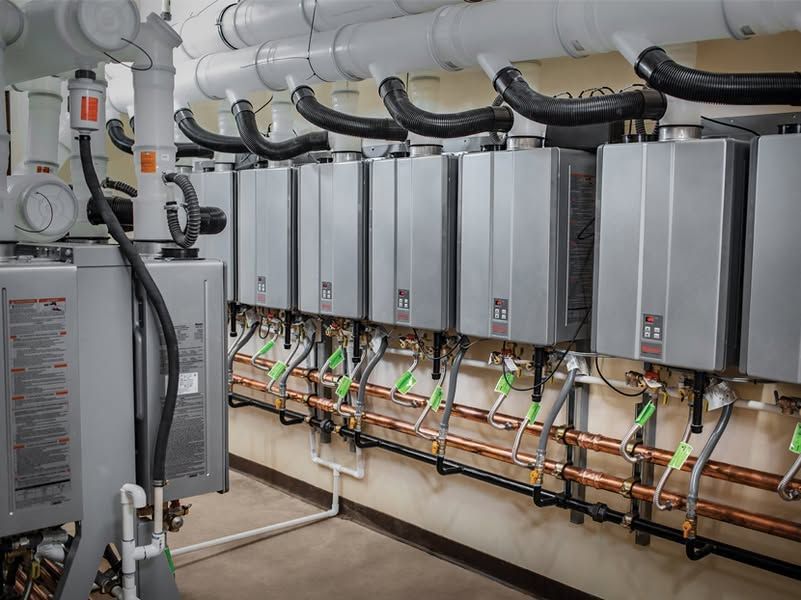 Row of gray industrial electrical control cabinets with wiring and pipes in a utility room